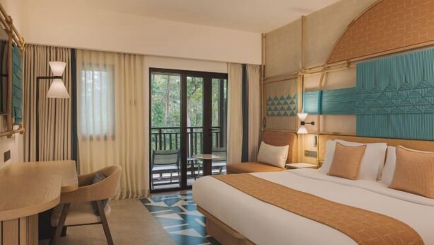 A hotel room with a large bed, a desk, and a balcony with a view of the outdoors. - Club Med Bintan (Bintan)