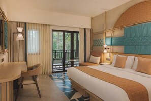 Een hotelkamer met een groot bed, een bureau en een balkon met uitzicht op de omgeving.