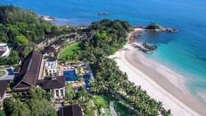 An aerial view of a coastal resort with a beach, pool, and lush greenery. - Club Med Bintan (Bintan)