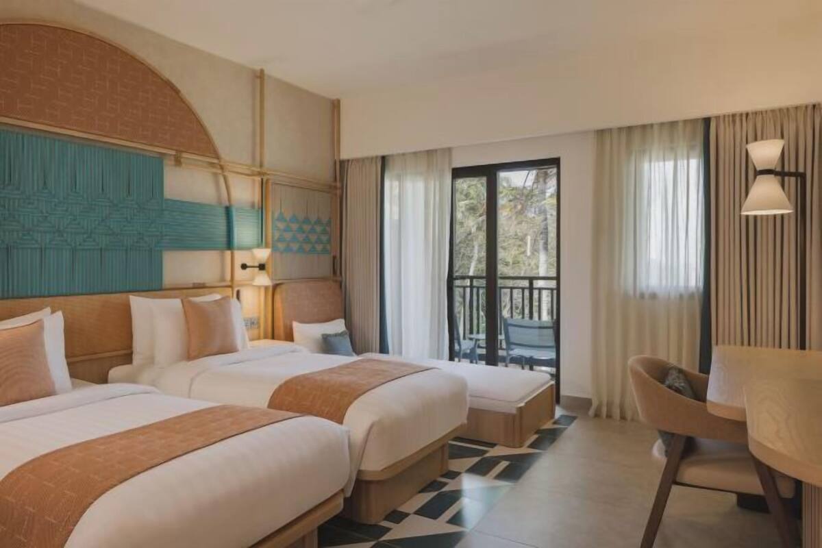 Ein Hotelzimmer mit zwei Betten, einem Balkon und einem Essbereich.