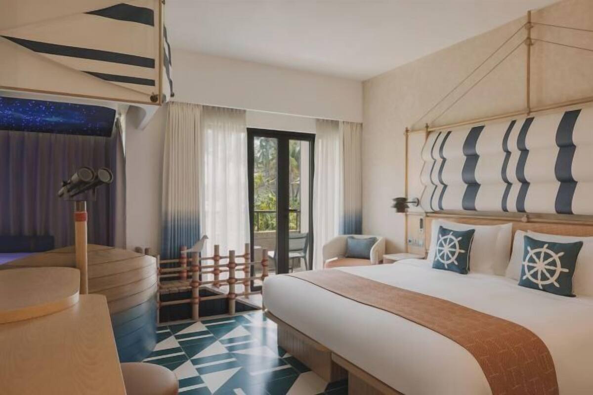 Ein Hotelzimmer mit einem Bett, einem Schreibtisch, einem Stuhl, einem Fenster und Blick auf Grünflächen.