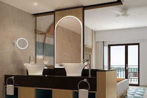 Un baño moderno con un espejo grande, dos lavamanos y un ventilador de techo.