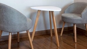 Two grey upholstered chairs with wooden legs and a white table with wooden legs.