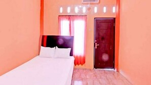 Een slaapkamer met een bed, een raam met gordijnen, een deur en een airconditioning.