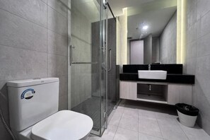 Une salle de bain moderne équipée de toilettes, d’une douche à parois en verre, d’un lavabo et d’un miroir.