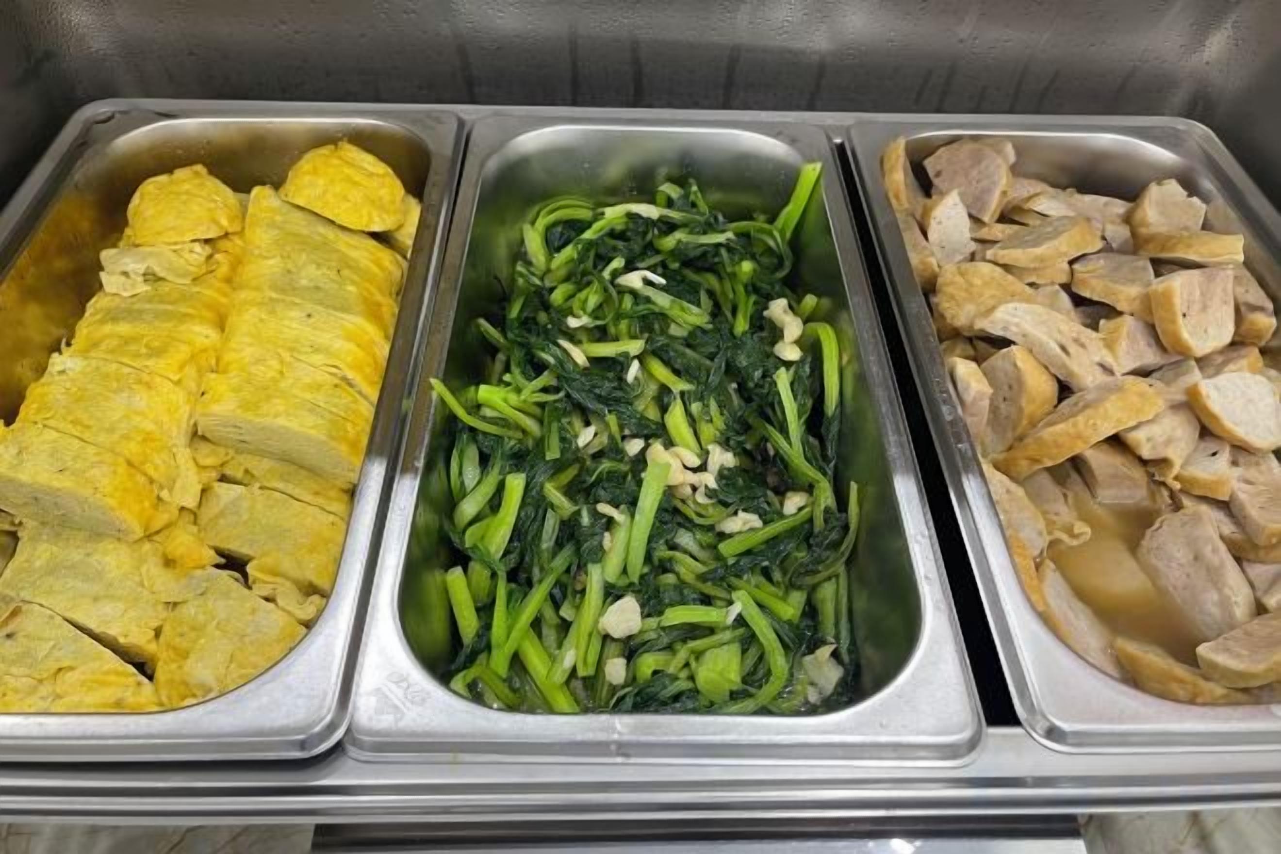 A buffet with three food trays containing different dishes.