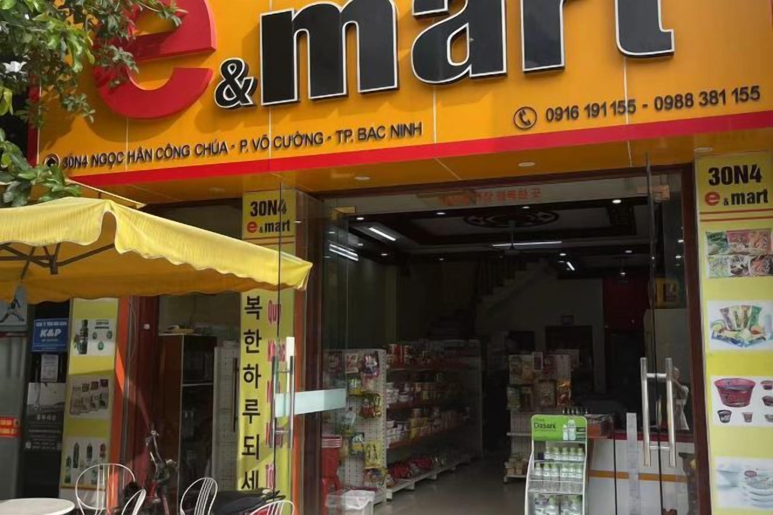 A storefront with a prominent 'e-mart' sign, a yellow awning, and a variety of products displayed inside.