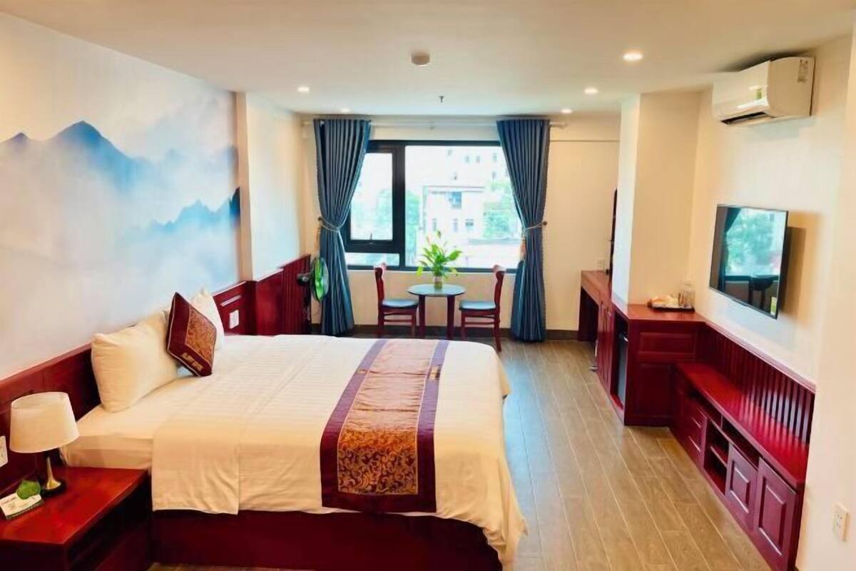 Une chambre d’hôtel équipée d’un lit, d’un bureau, d’une chaise, d’une télévision et d’une fenêtre avec des rideaux.