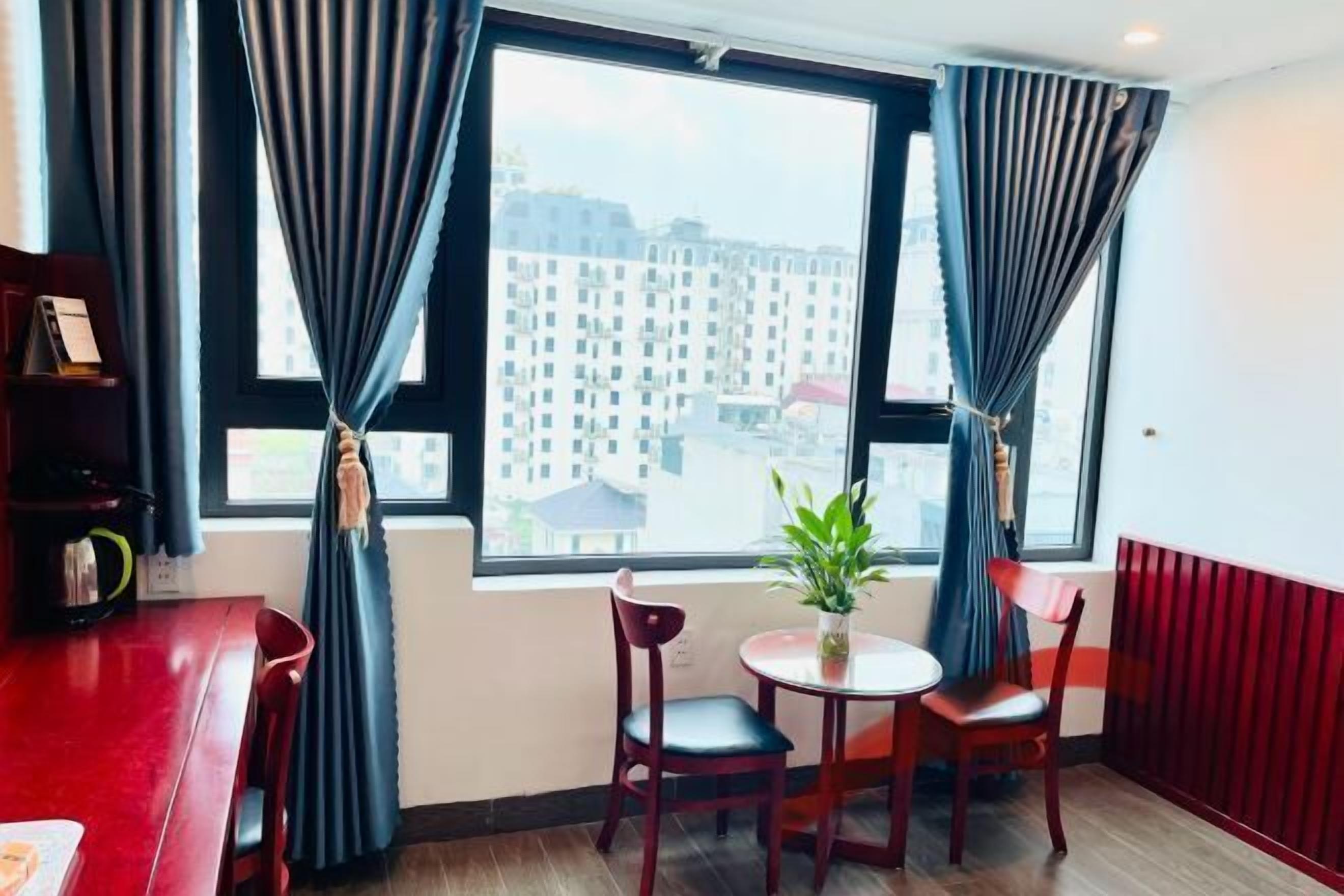 A room with a large window, two chairs, a small table, and a potted plant.