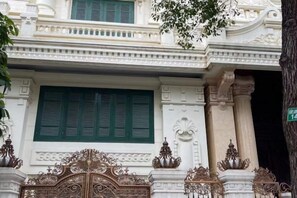 Fachada de edificio con detalles arquitectónicos ornamentales, incluyendo una reja decorativa y columnas.