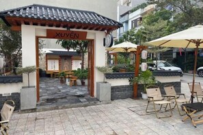 A traditional Vietnamese entrance with a tiled roof, a sign reading 'XUYEN,' and outdoor seating with umbrellas. - Glory 3 Hotel Korea Street (Bac Ninh)