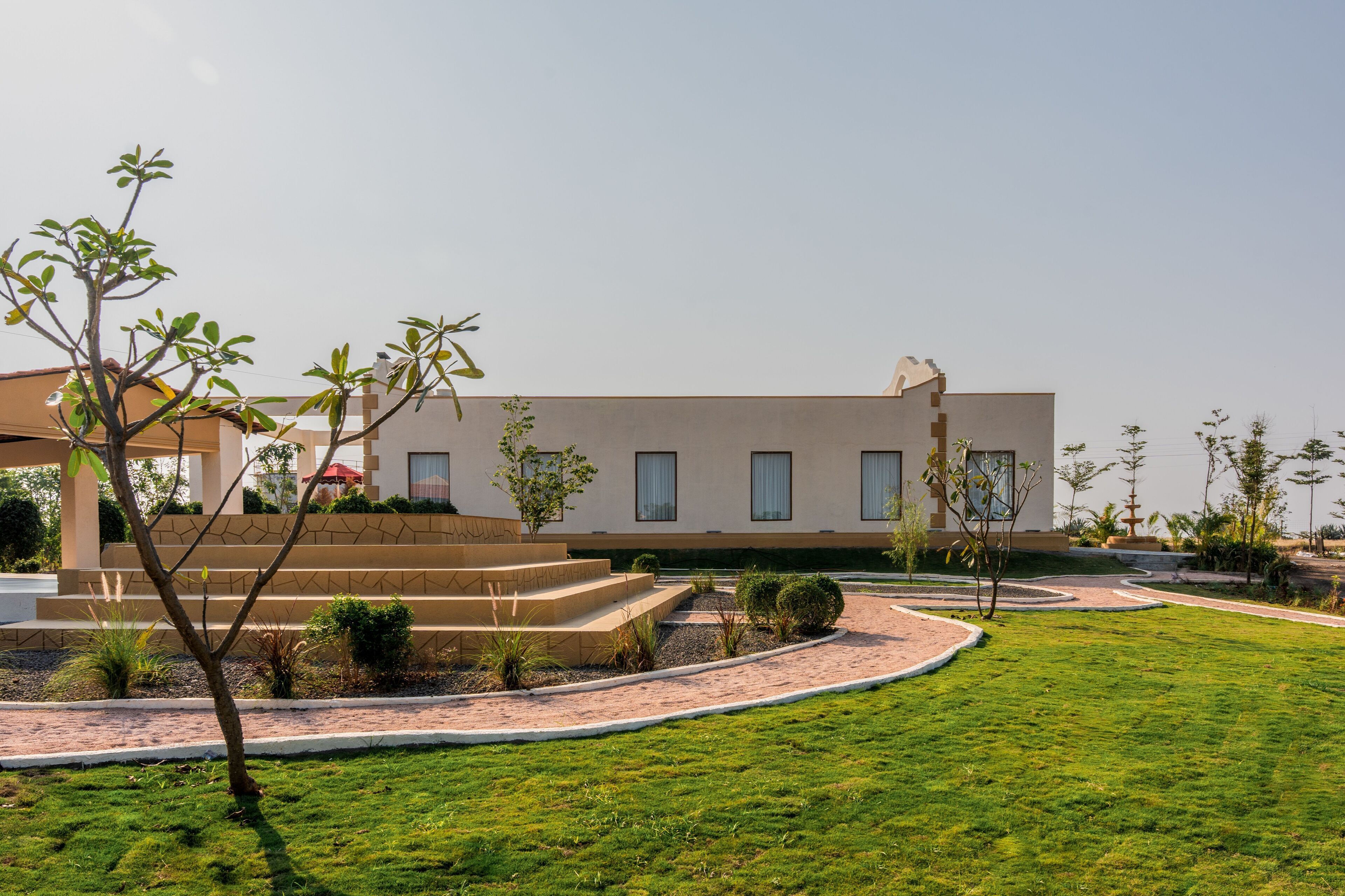 A modern building with a flat roof, large windows, and a well-maintained lawn with a few trees and shrubs.