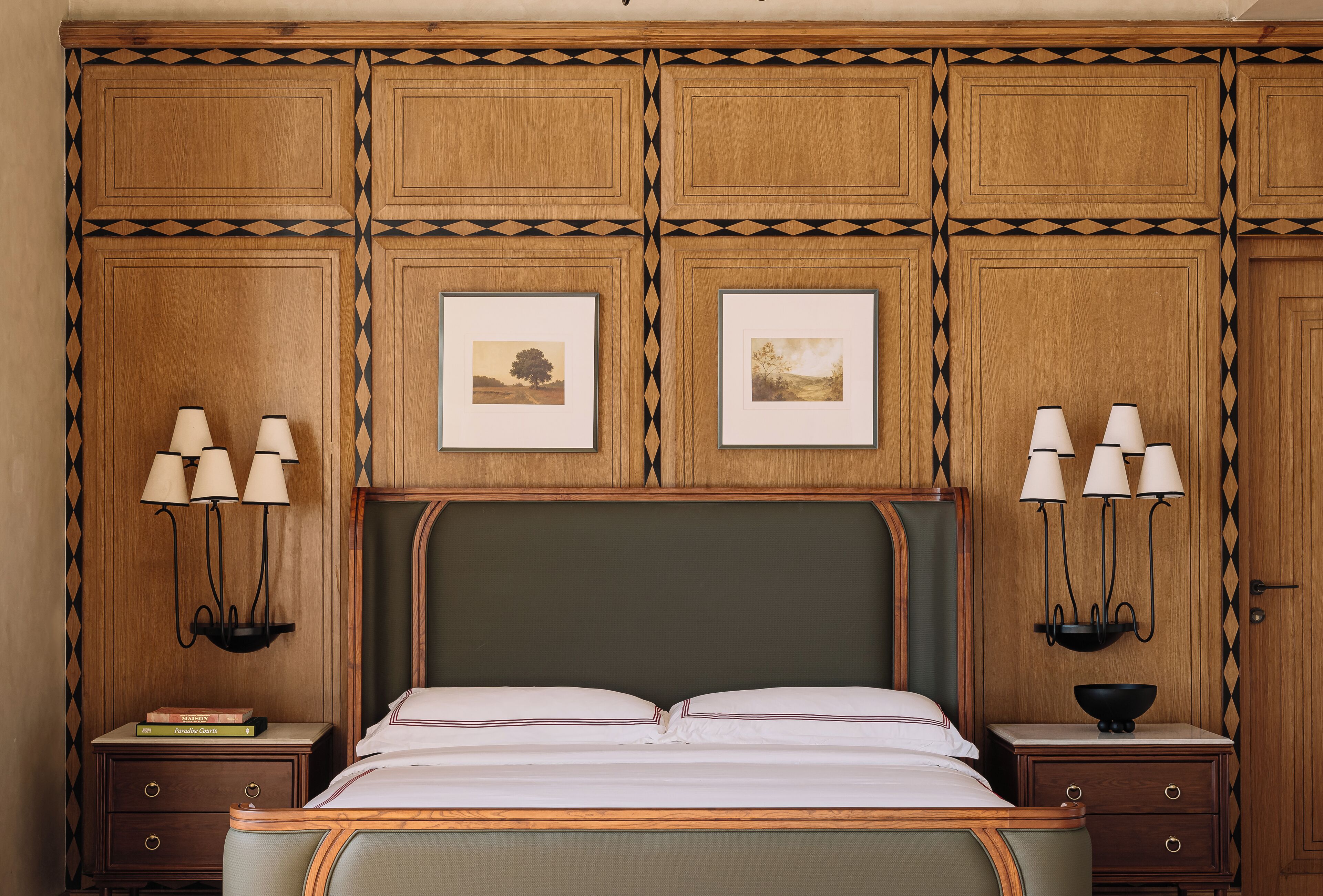 Quarto bem arrumado com uma cama grande, duas mesas de cabeceira com luminárias, quadros nas paredes e design de painel de madeira.
