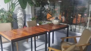 A dining area with a wooden table and chairs, surrounded by potted plants and a decorative vase. - BUSAN YONGDO HAYANSUNG HOTEL (Busan)