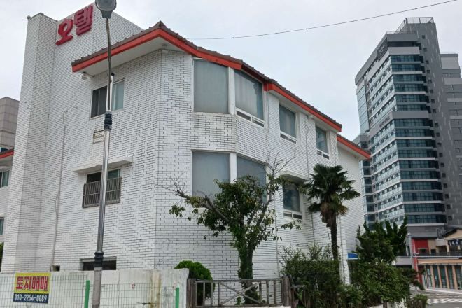 A white building with a red roof and a sign with Chinese characters.