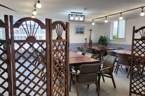 A dining area with wooden tables and chairs, a view of the outdoors, and a ceiling light fixture. - BUSAN YONGDO HAYANSUNG HOTEL (Busan)
