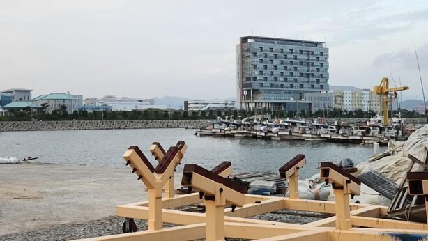 A waterfront area with a modern building, boats, and wooden structures. - BUSAN YONGDO HAYANSUNG HOTEL (Busan)
