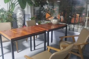 A dining area with a wooden table and chairs, surrounded by large windows and potted plants. - BUSAN YONGDO HAYANSUNG HOTEL (Busan)