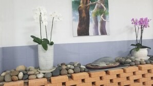 A room with a white and blue wall, two potted orchids, a painting of trees, and a brick wall. - BUSAN YONGDO HAYANSUNG HOTEL (Busan)