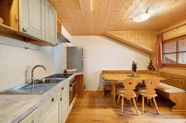 A kitchen with wooden cabinets, a stainless steel sink, and a wooden dining table with chairs.