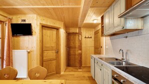 A wooden interior with a kitchen area, including cabinets, a sink, and a dining table. - Apartment 'Jelerhof Hochstein' with Mountain View, Shared Garden and Wi-Fi (Gsies)