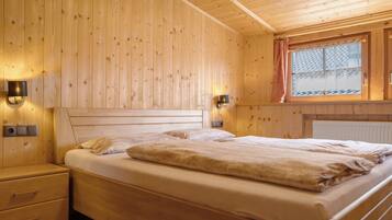 A wooden-paneled room with a bed, bedside tables, and a window with a view.