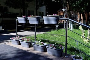 Outdoor planters with flowers on a metal stand. - Yingbin Garden Hotel (Almaty)