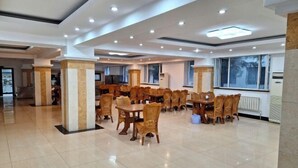 Un vaste espace dédié à la salle à manger, avec de nombreuses tables et chaises, un sol carrelé et un design moderne au niveau du plafond.