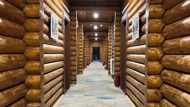 L’intérieur d’une cabane en rondins, avec un couloir central, des murs en bois et un plancher à motifs.