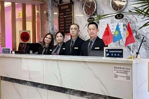 A reception desk with flags, a clock, and a sign indicating a business center. - Yingbin Garden Hotel (Almaty)