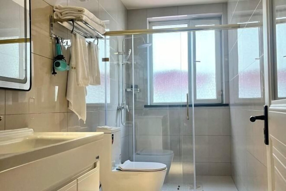 A modern bathroom with a glass-enclosed shower, a toilet, and a sink.