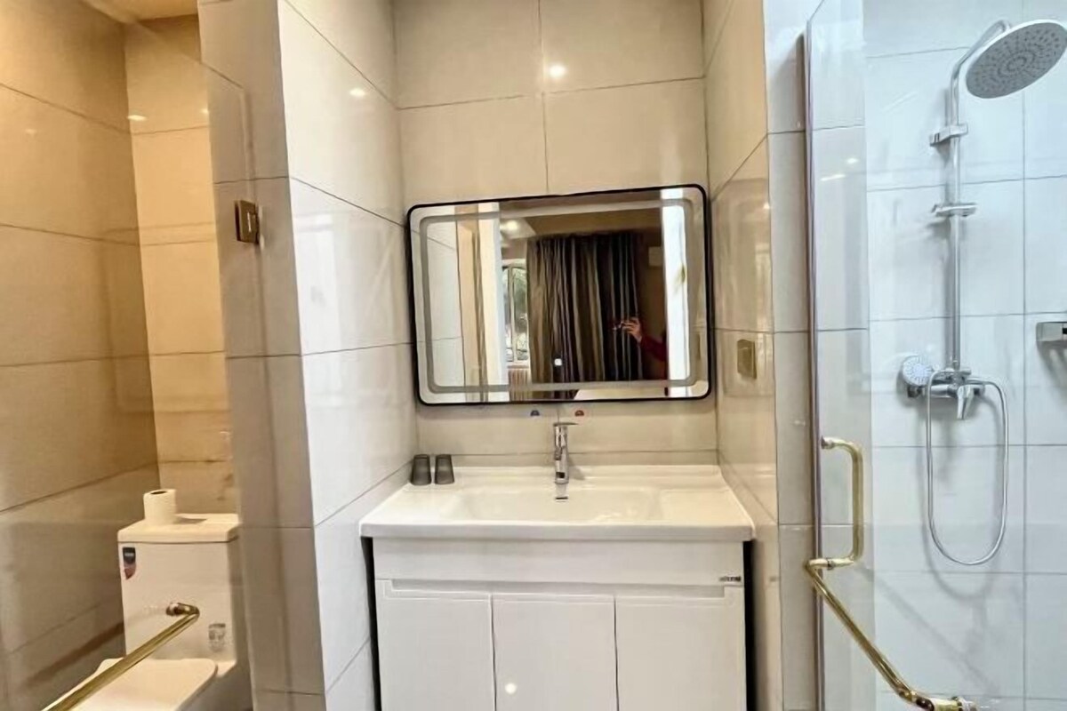 A modern bathroom with a white sink, mirror, and shower.
