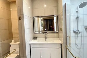 Un bany modern amb un vàter blanc, mirall i dutxa.