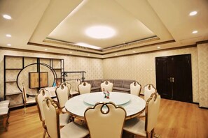 A conference room with a round table, chairs, a sofa, and a black door.