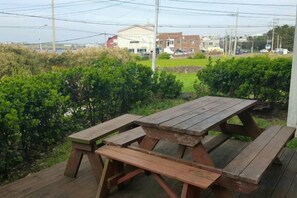 Ein Holztisch zum Picknicken auf einer Terrasse mit Blick auf ein Gebäude und Grünflächen im Hintergrund.