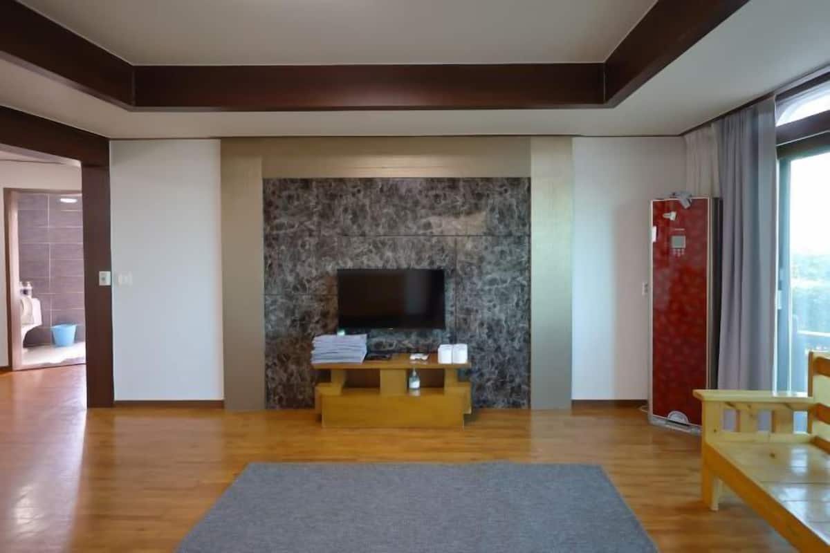Una sala de estar moderna con un televisor de pantalla plana, un mueble de entretenimiento de madera, un tapete gris y un banco de madera.
