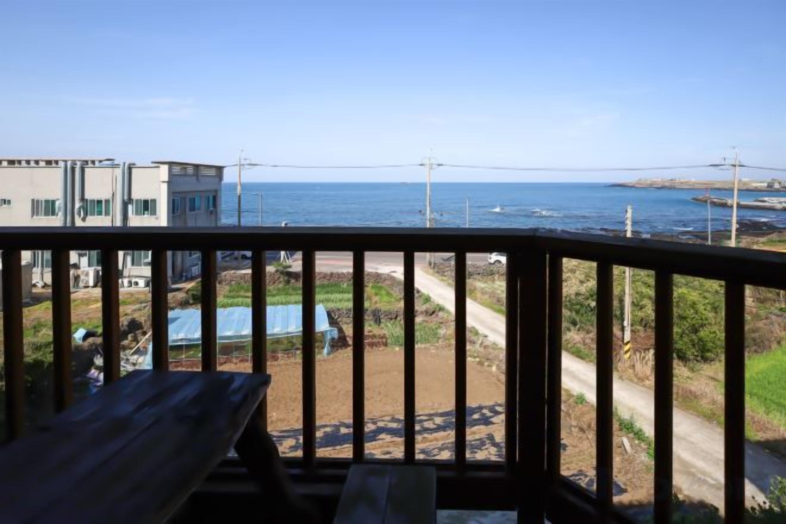 A balcony with a view of the sea and a building in the background.