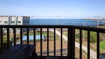 A balcony with a view of the sea and a building in the background.