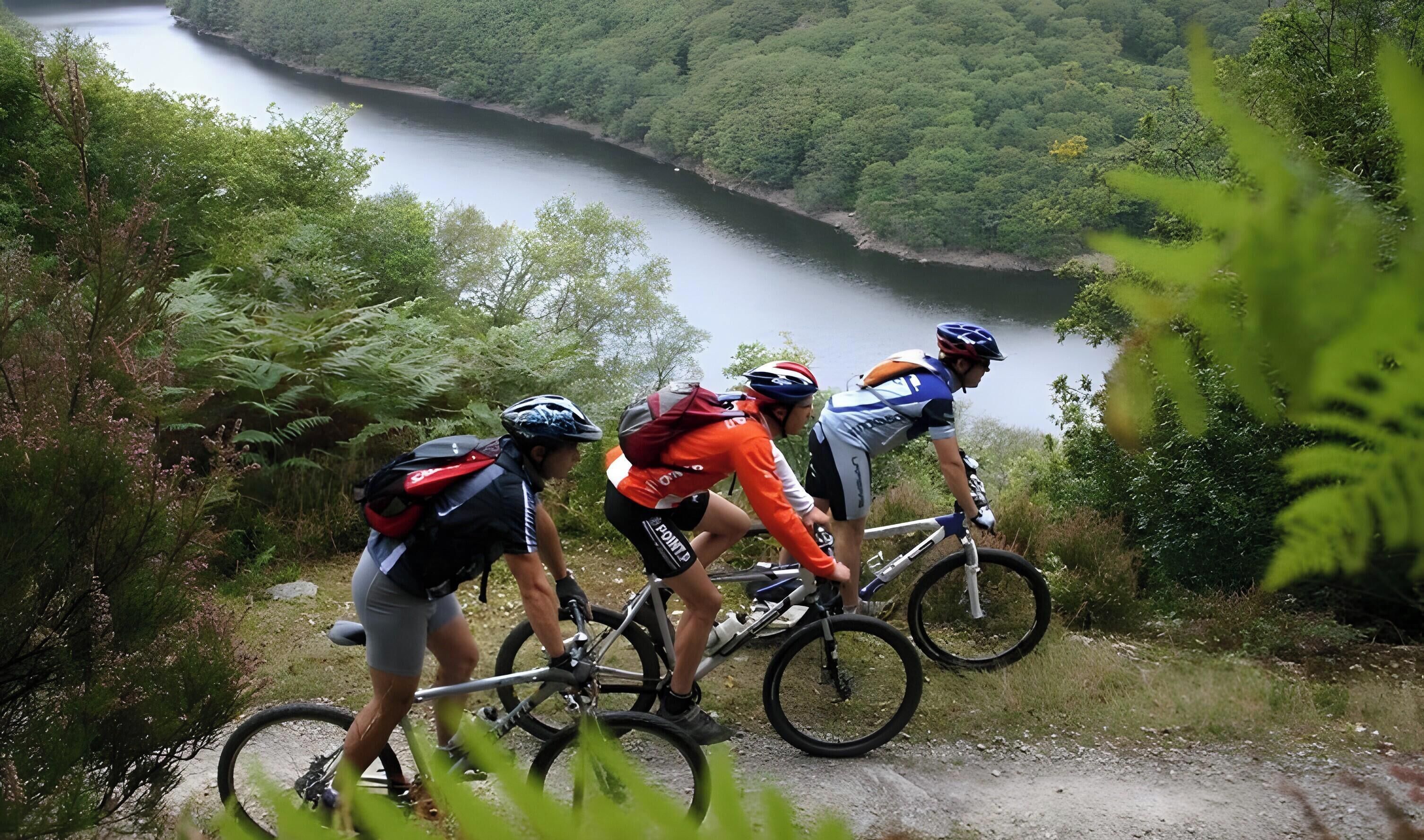 A group of cyclists on a trail with a river in the background.