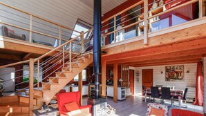 En rummelig stue i loftstil med en trætrap, et køkken og et spiseområde.