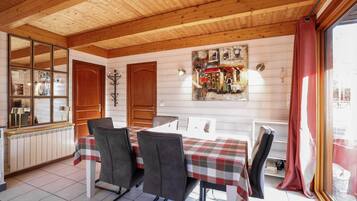 Een eetgedeelte met een houten plafond, een tafel met een geruit tafelkleed en stoelen.