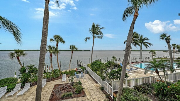 A pool area with lounge chairs and a view of the water. - HVC #203 - Spa/Pool - Private Paradise on LBK! (Longboat Key)