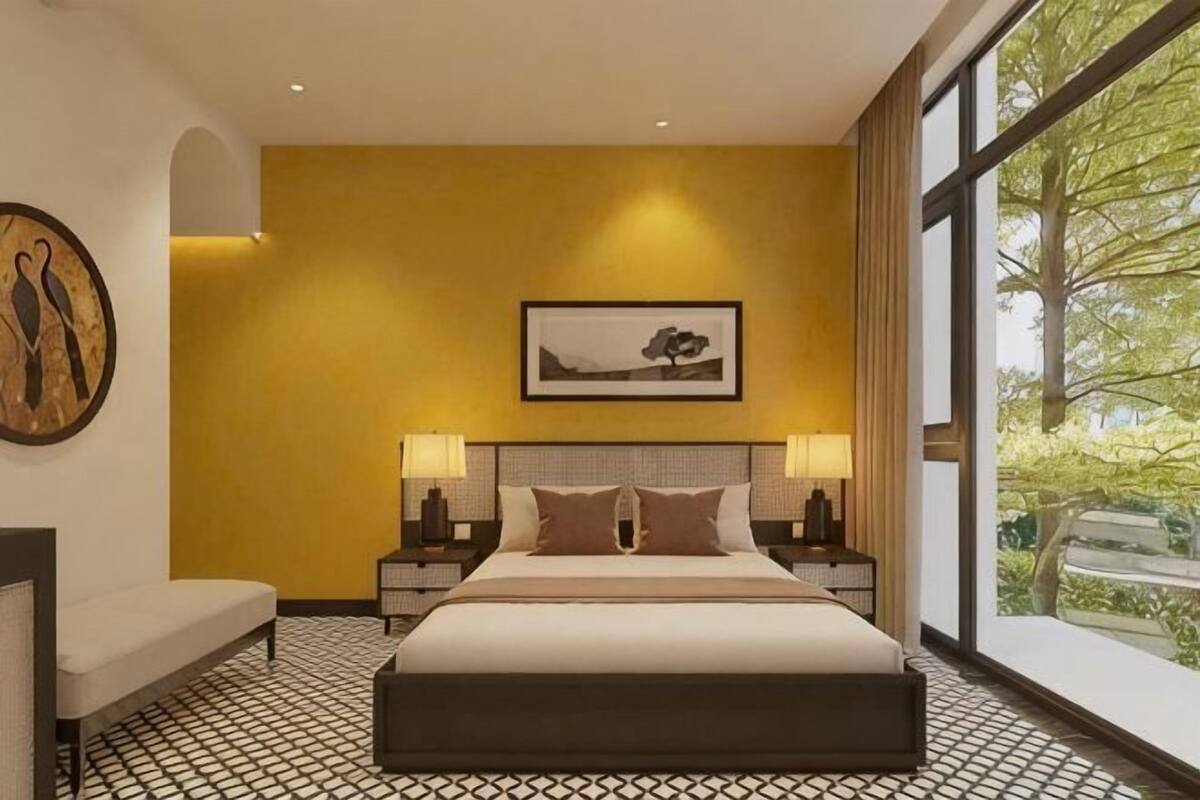 Une chambre d’hôtel comprenant un lit, des tables de chevet, un banc, une grande fenêtre avec vue et des œuvres d’art accrochées aux murs.