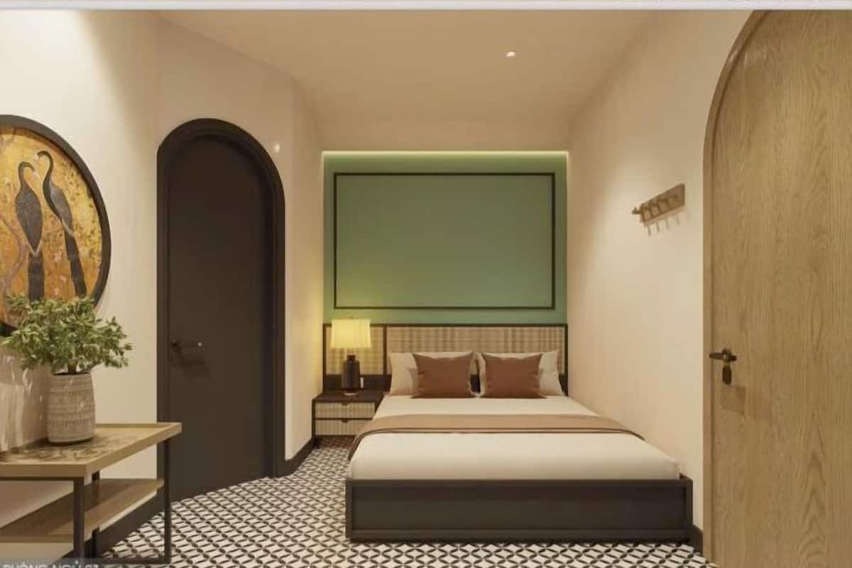 Une chambre à coucher comprenant un lit, une table de chevet, une lampe et un téléviseur fixé au mur.