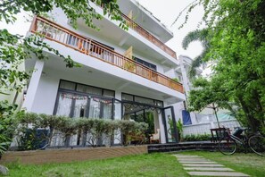 A two-story building with a balcony, a covered entrance, and a garden area. - Palm Riverside Boutique (Hoi An)