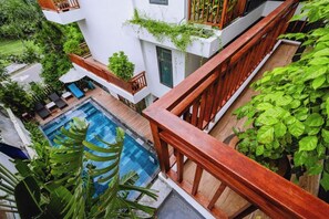Edifici modern amb piscina, barana de fusta i vegetació abundant.