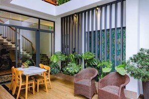 A modern interior with a dining area, wicker chairs, and a staircase. - Palm Riverside Boutique (Hoi An)