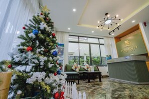 Un espace d’accueil avec un sapin de Noël, un comptoir de réception et une vue sur l’extérieur.