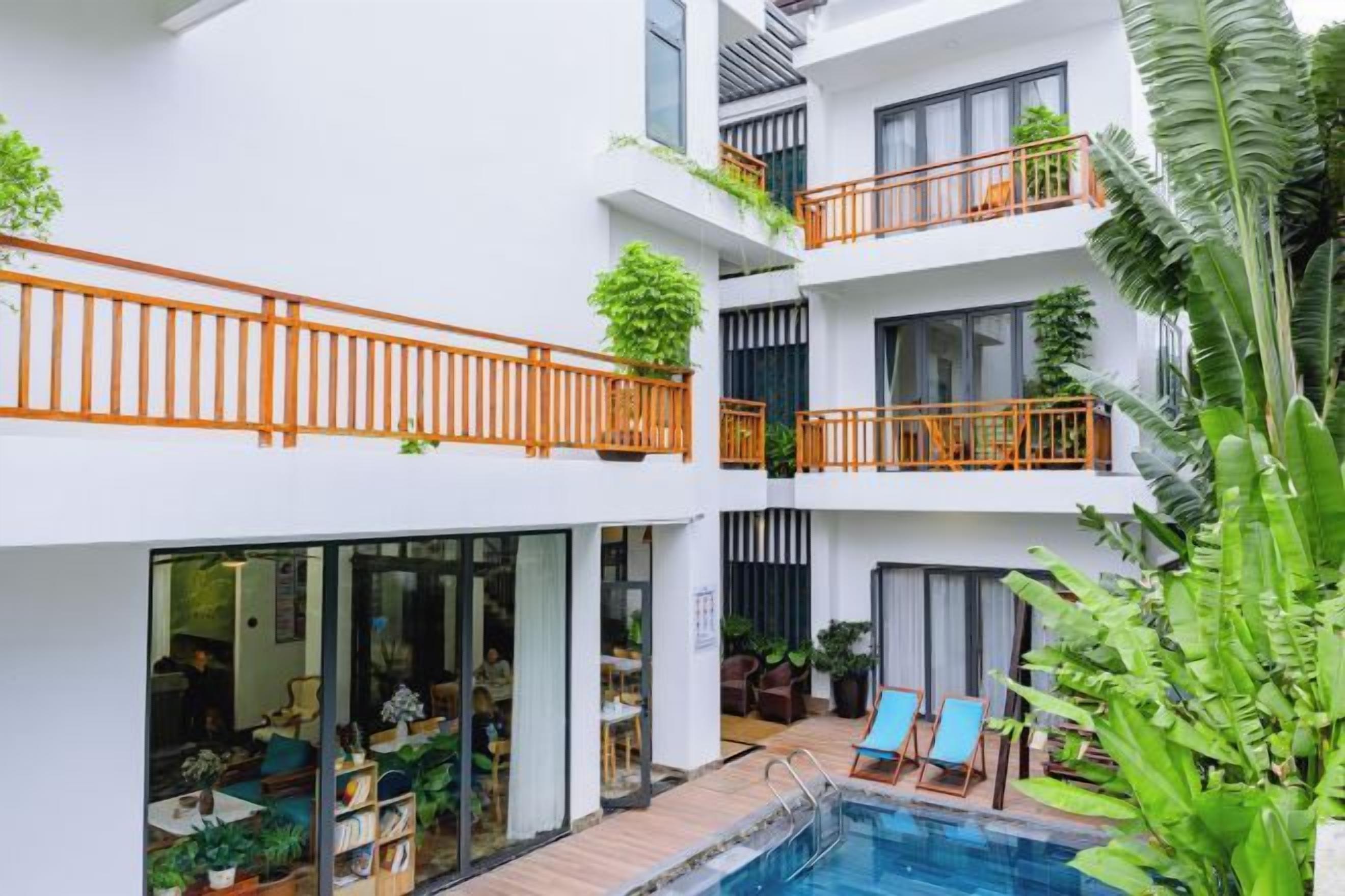 Un hotel de varios pisos con balcones, piscina y zonas de estar interiores.