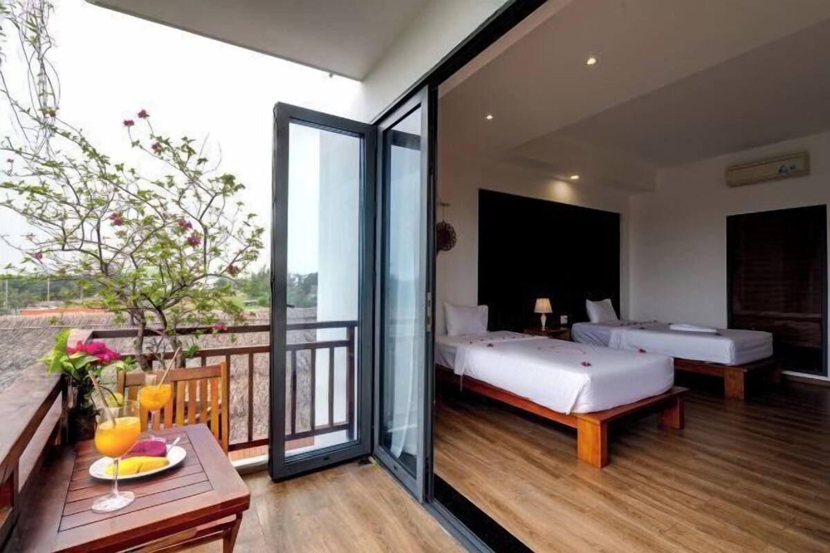 Ein Hotelzimmer mit Balkon, zwei Betten, Holzboden und einem großen Fenster.